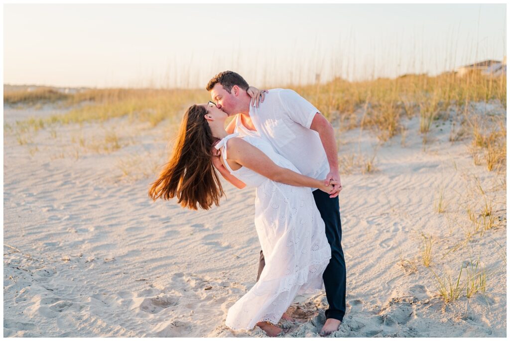 husband and wife kissing on the sand in North Carolina