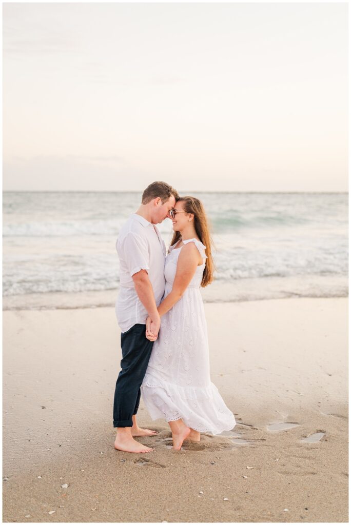 couple standing barefoot in the sand at sunset 