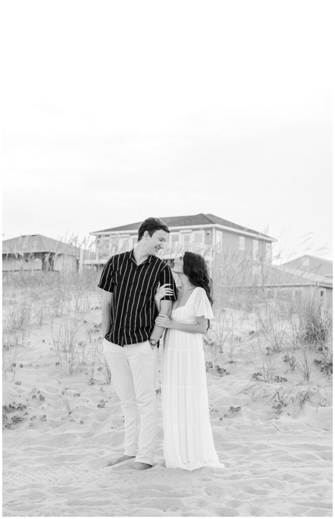 engagement couple posing on the beach in front of houses in Wilmington