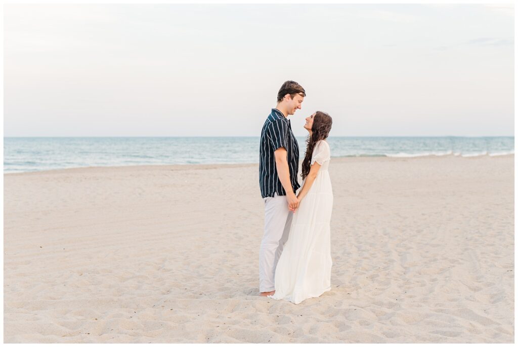 couple posing on the beach near the water for engagement session