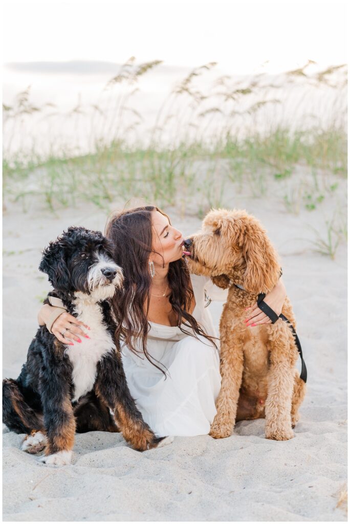 dog licking his owner while posing on the beach for engagement session