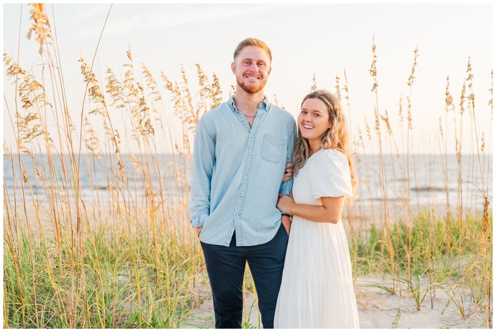 couple posing next to sea grass on the dunes in Oak Island, NC