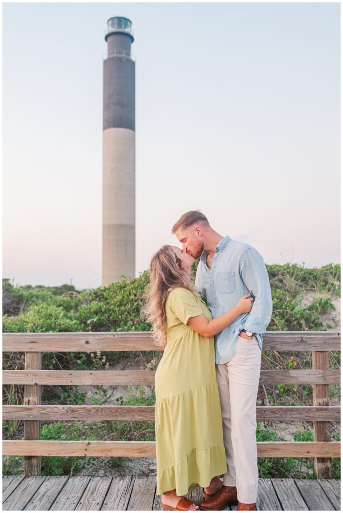 engagement couple posing on a boardwalk near the lighthouse in Oak Island, NC