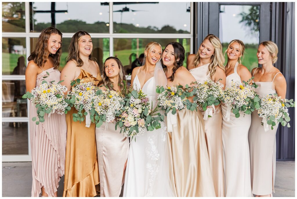 bridal party posing and smiling under cover at The Meadows Raleigh venue