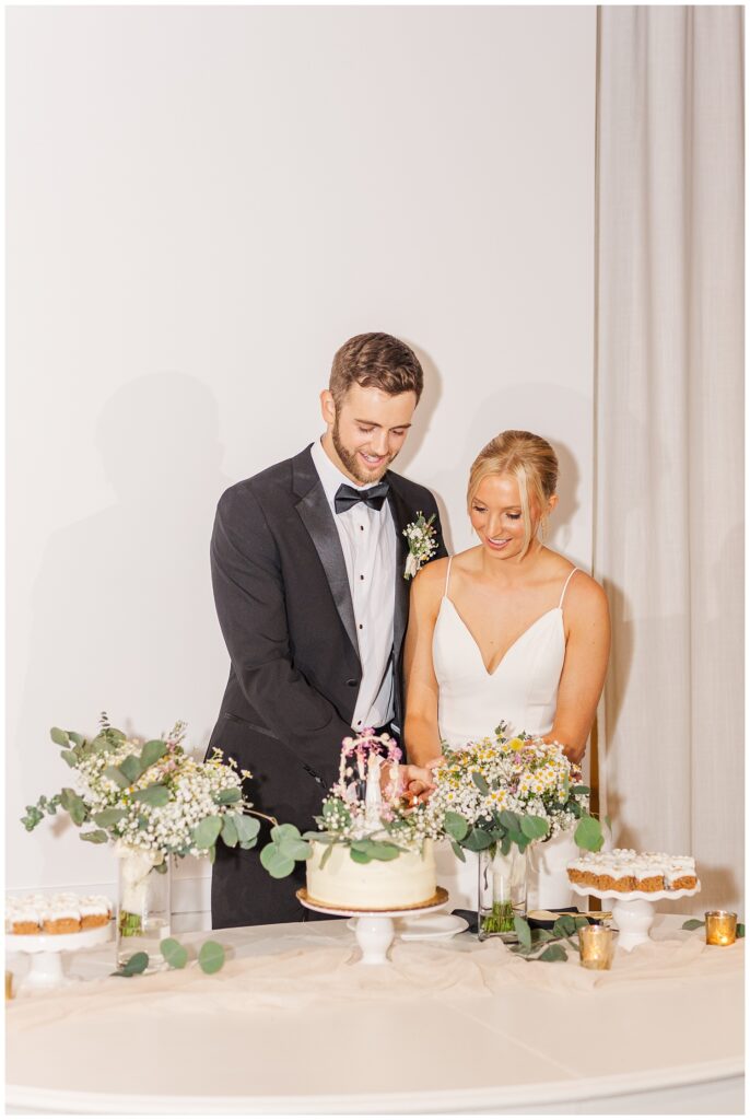 bride and groom cut cake at The Meadows Raleigh wedding venue