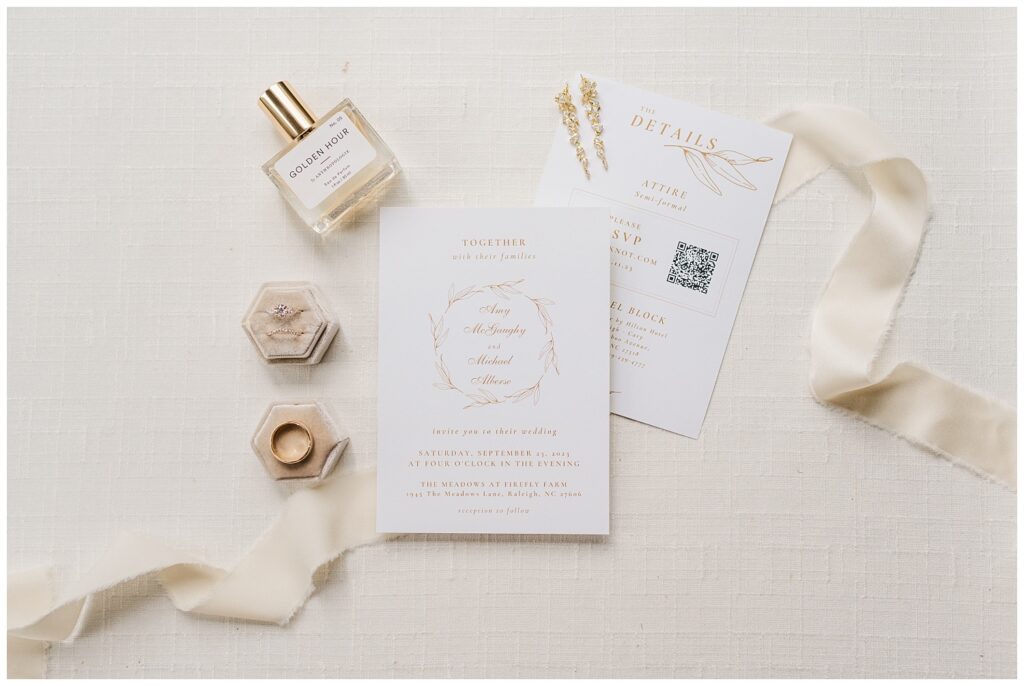 wedding flat lay with invitation, perfume, and rings