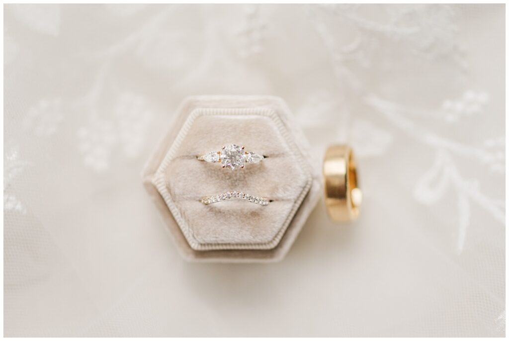 wedding rings sitting on top of light pink box and alce