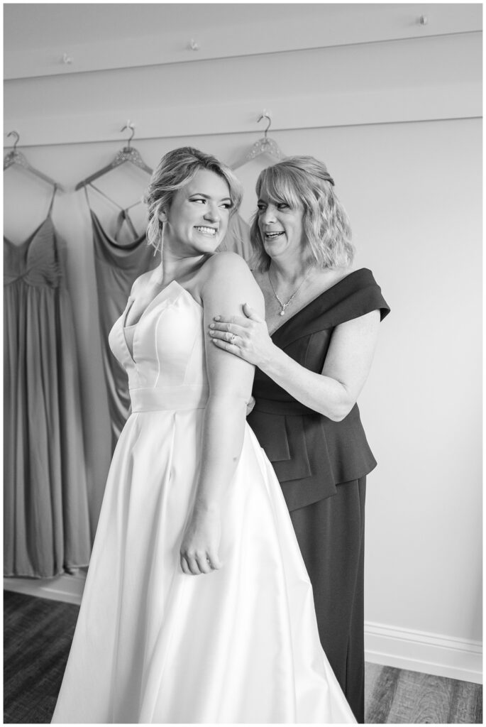 bride's mom smiling at bride while they get ready for fall wedding