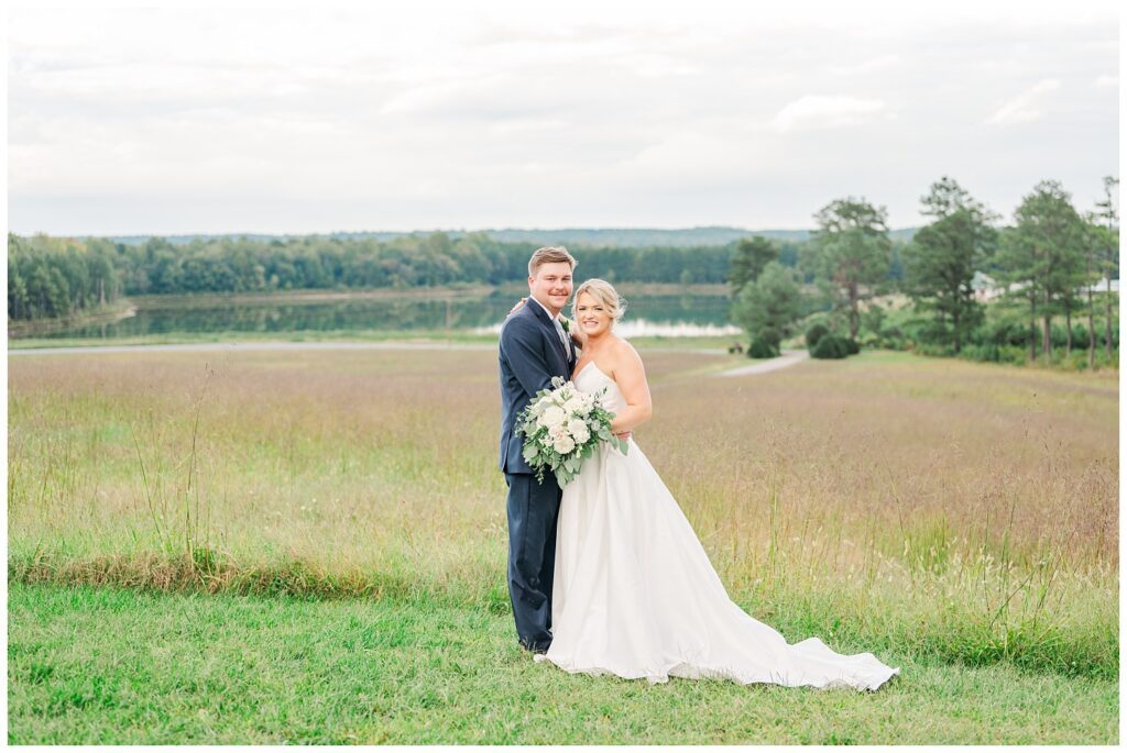 bride and groom posing together in front of a field on a hill in Richmond VA