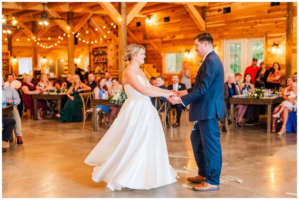 bride and groom share first dance during wedding reception in barn
