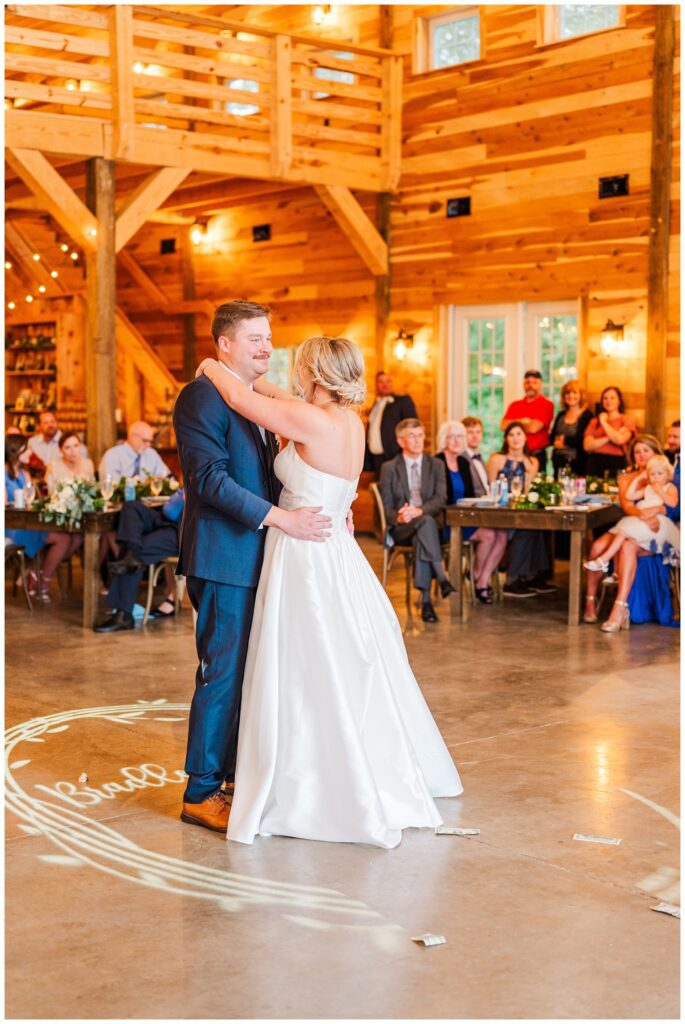 bride and groom share first dance during wedding reception in barn