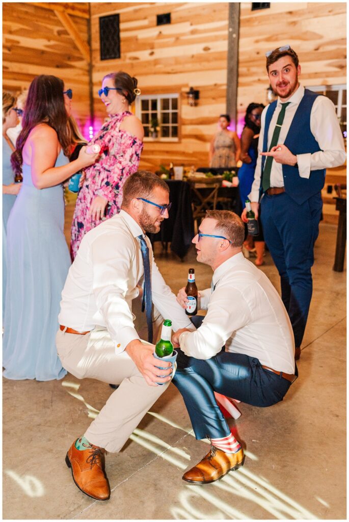 groomsmen wearing blue sunglasses and drinking beer while dancing at reception