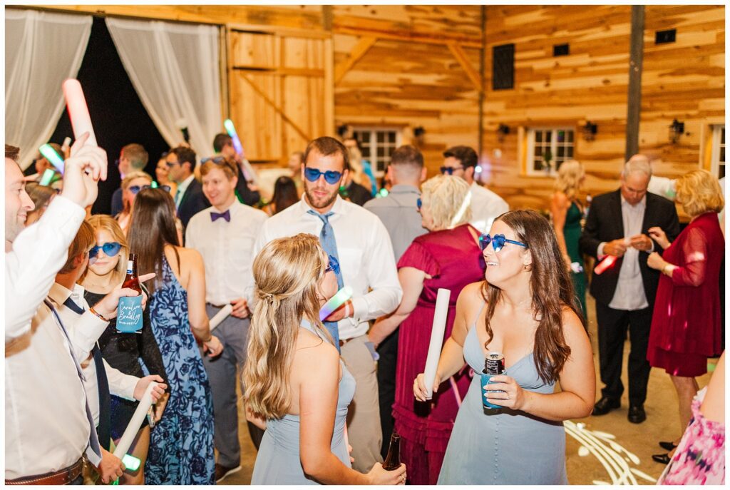 wedding guests wearing blue sunglasses and dancing at reception