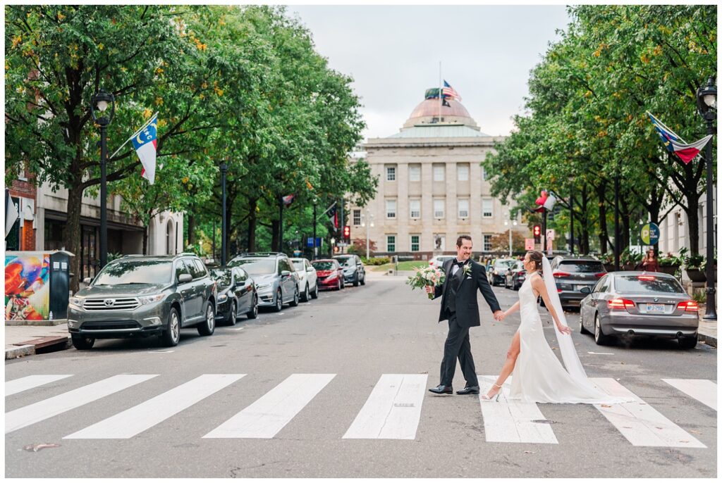 wedding couple crossing the street in front of City Hall in Raleigh