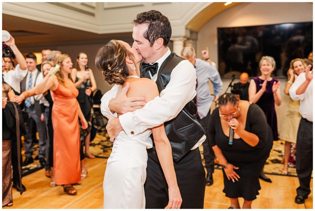 bride wearing shorter reception dress and kissing the groom at Raleigh NC reception venue