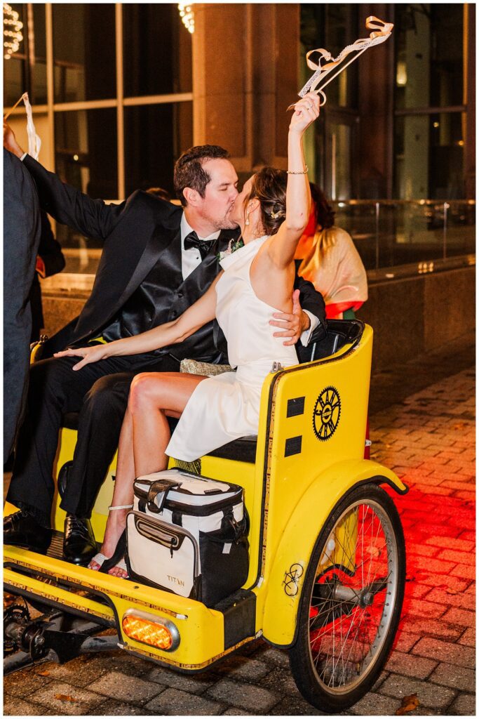 wedding couple kissing in a yellow rickshaw in downtown Raleigh NC