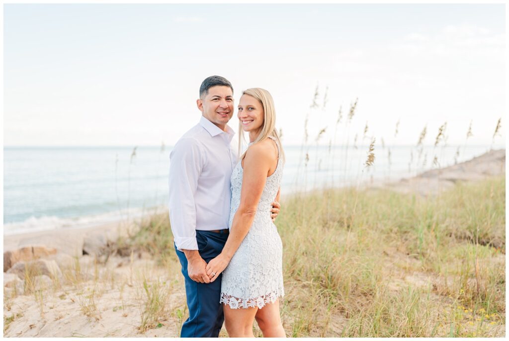 engaged couple holding hands and smiling on the beach at Fort Fisher