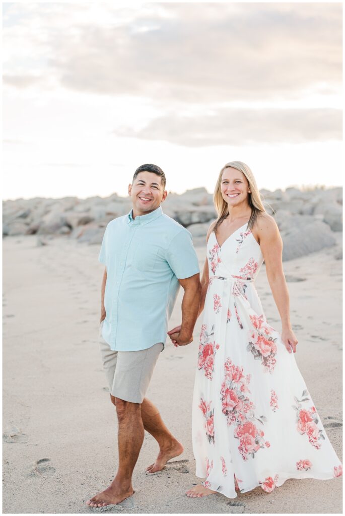 woman wearing a white and pink floral dress for beach engagement session in NC