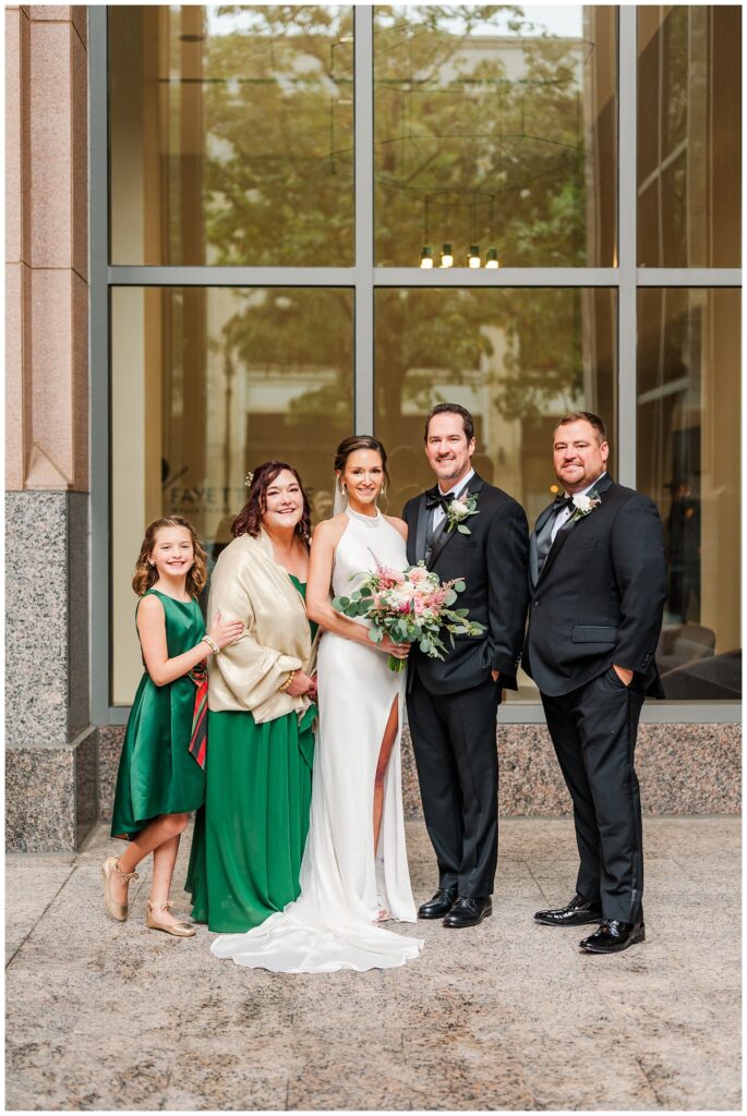 groom and bride posing with attendants downstairs under the awning 