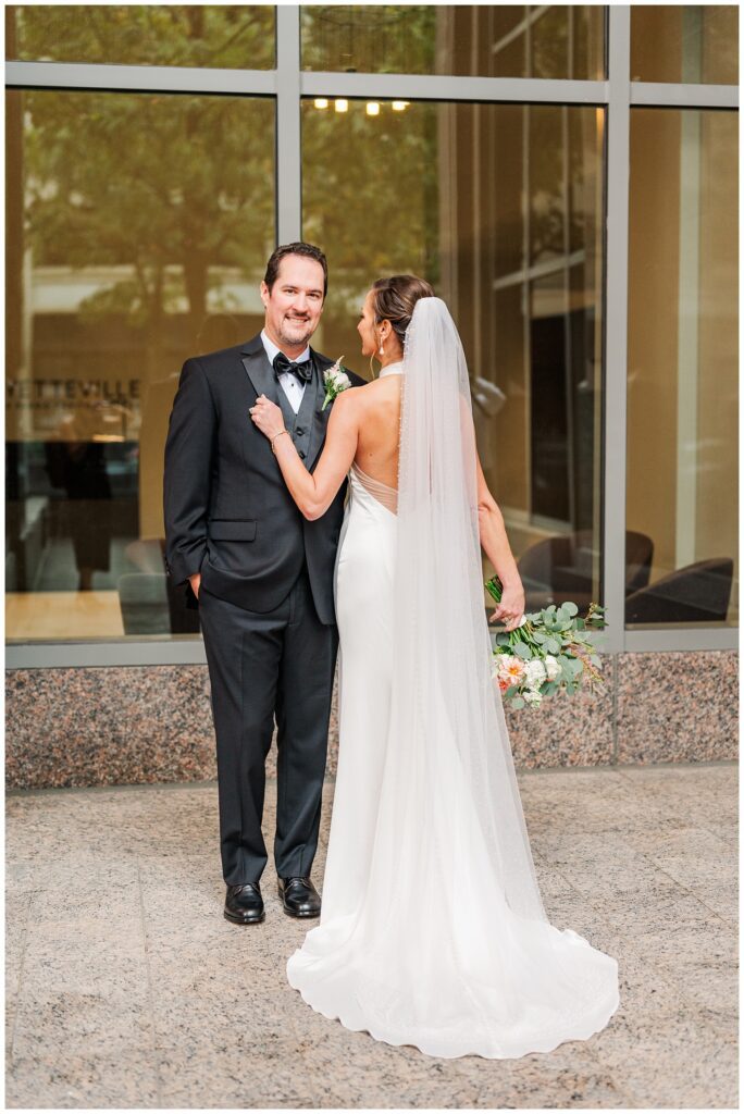 groom posing with bride outside at the Club City Raleigh in downtown 