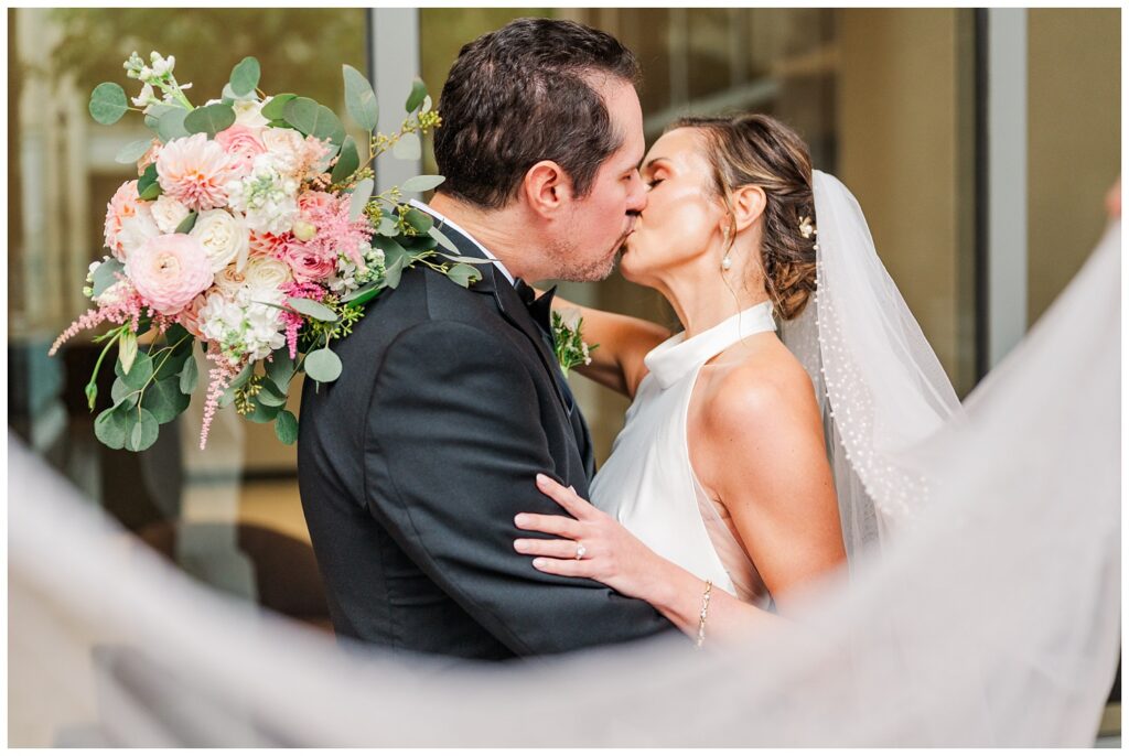 bride and groom share kiss wrapped in a veil at downtown Raleigh fall wedding