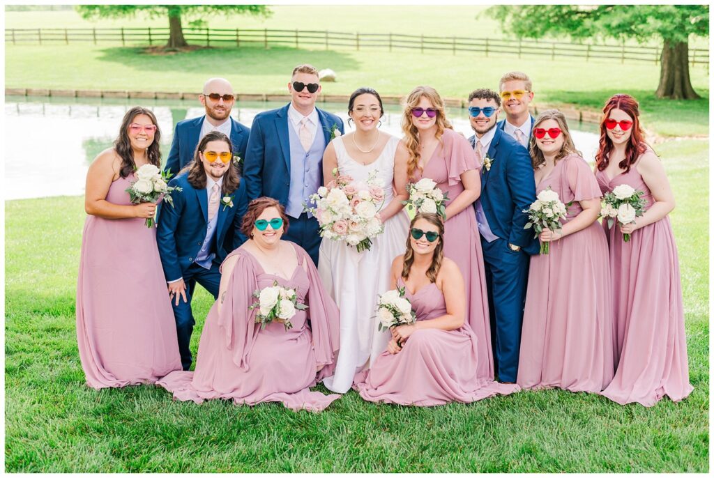 full wedding party posing with bouquets and boutonnieres next a pond in Wilmington