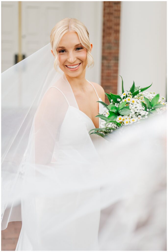 bride wrapped around her veil at portrait session at Meredith College in Raleigh