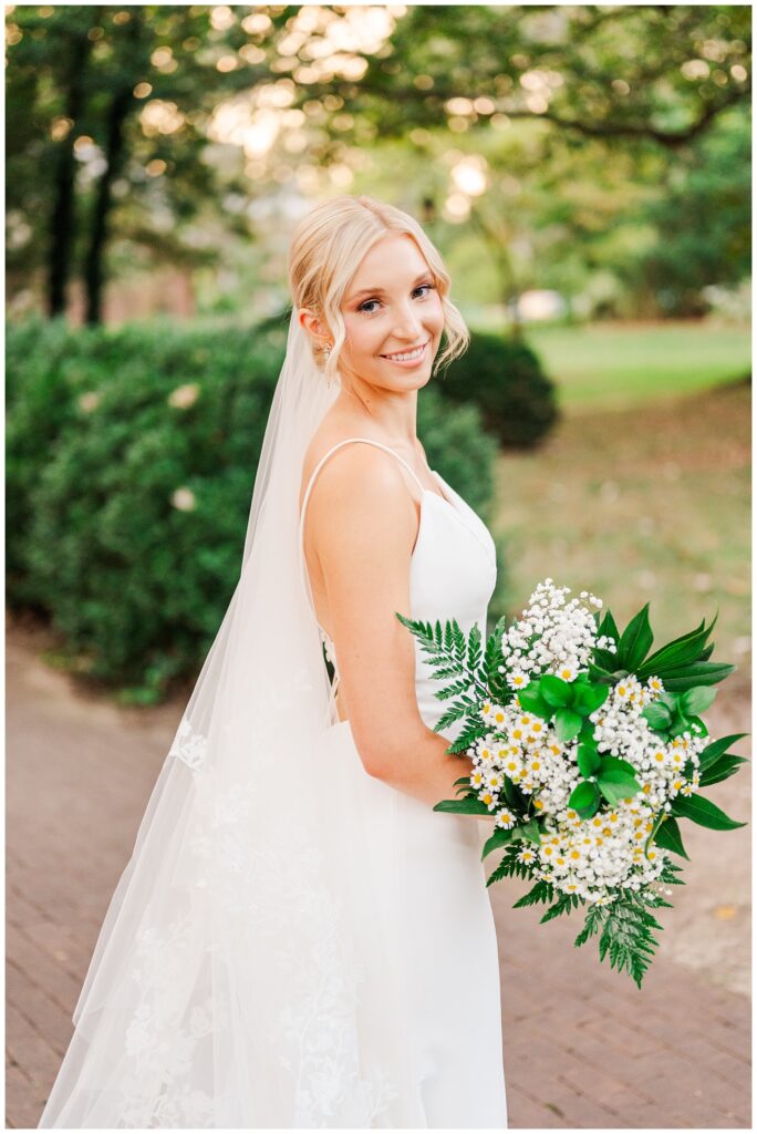 bride posing to the side holding her white and green bouquet in Raleigh