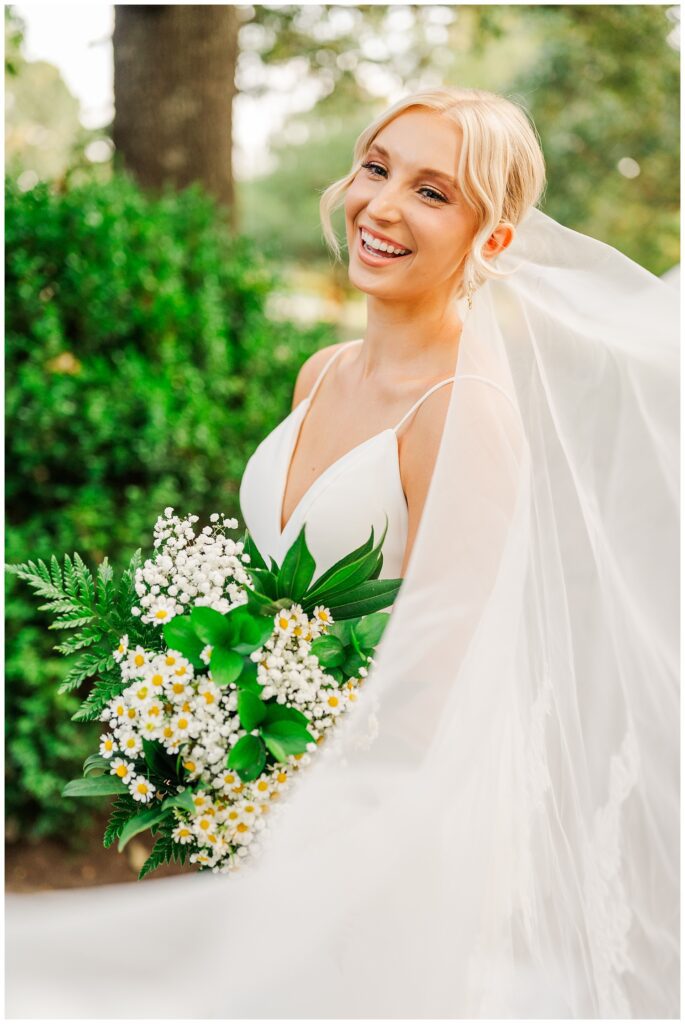 bride laughing while posing for bridal portraits at Raleigh's Meredith College