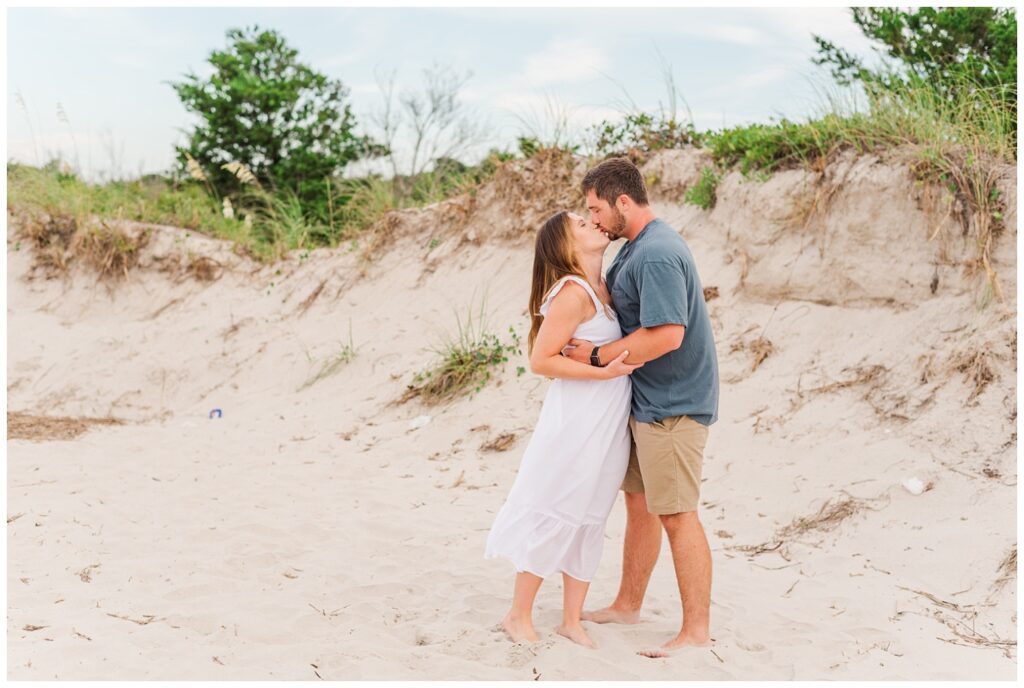 engaged couple sharing a kiss among the sand dunes at Wrightsville Beach