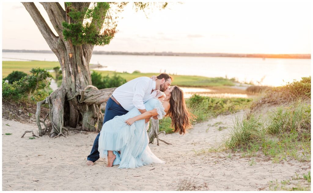 guy dipping back his fiance at Fort Fisher engagement session at sunset