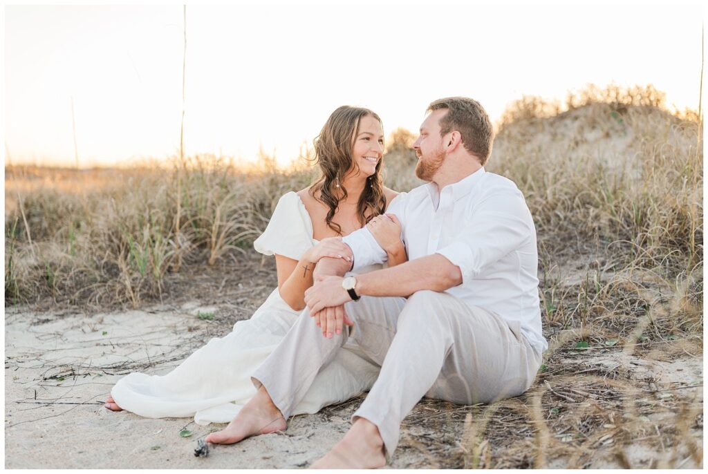 couple sitting on brown grass at Wrightsville Beach engagement