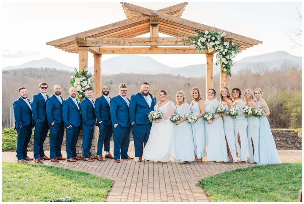 full wedding party posing at the ceremony site at the Glass Hill Venue