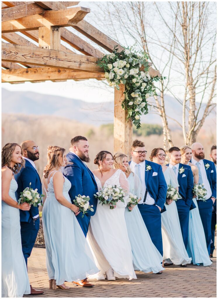 bride and groom posing with the wedding party at the outdoor ceremony site 