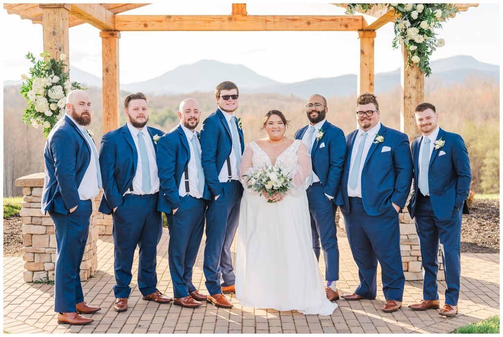 bride posing with the groomsmen outside at the ceremony site at Virginia wedding venue