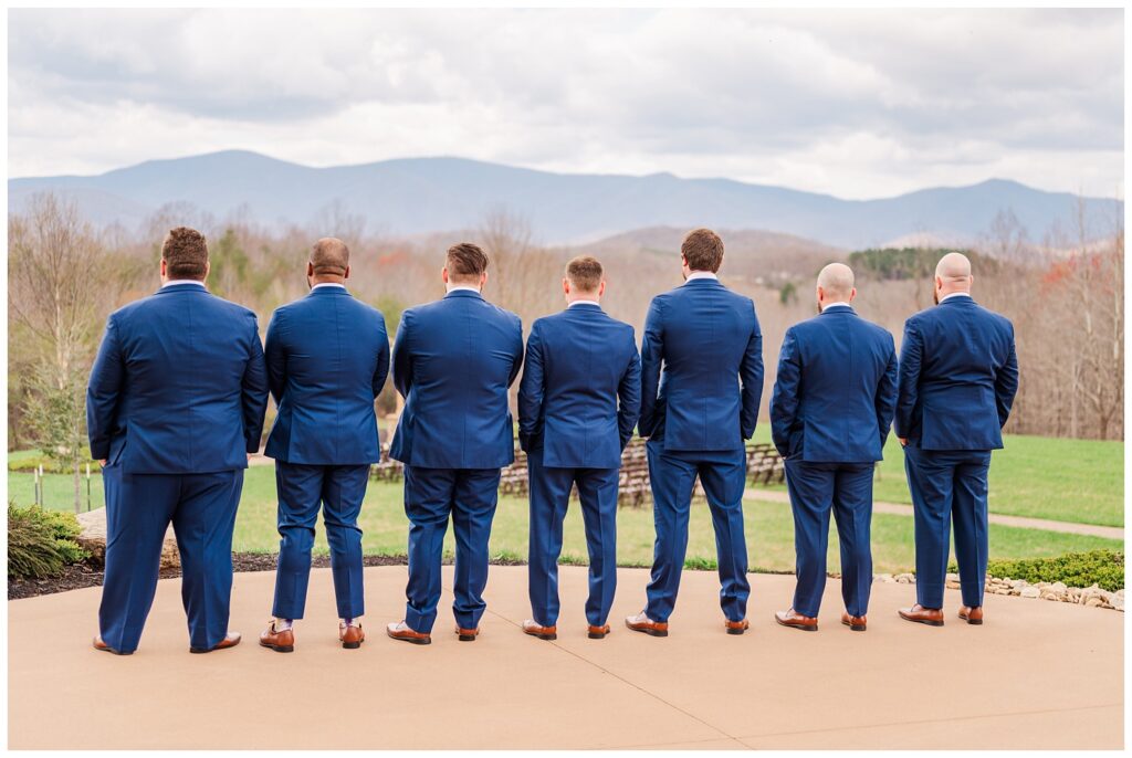 groom and his groomsmen turned away outside of a wedding venue 