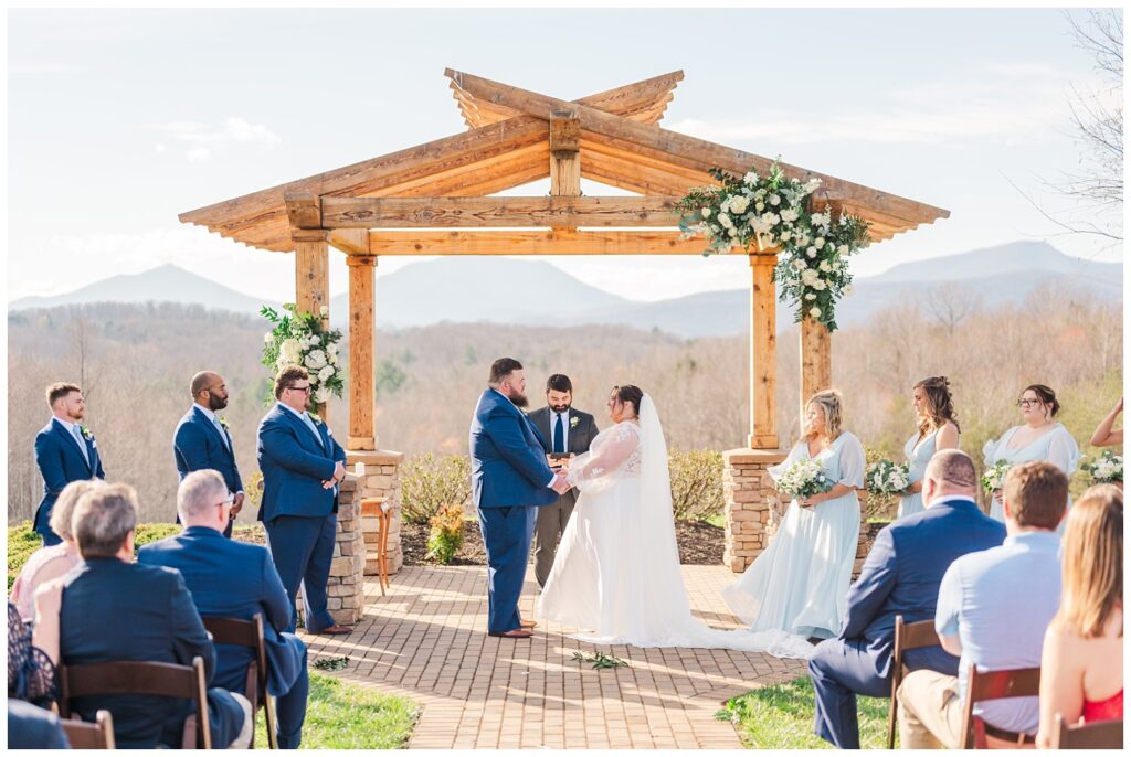 bride and groom holding hands at the outdoor altar during ceremony 