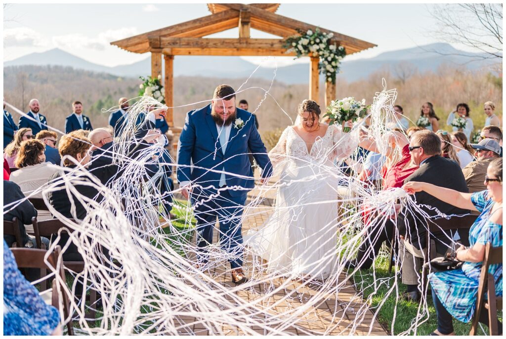 wedding guests shooting streamers at the bride and the groom while they walk down the aisle