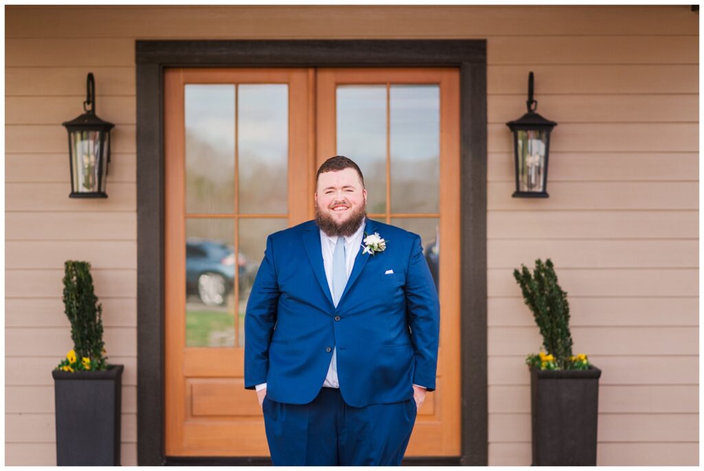 groom posing outside the front of the wedding venue 