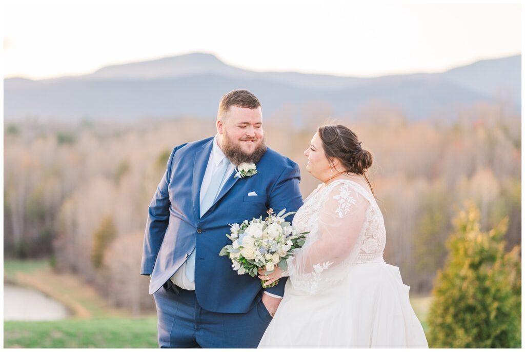 bride and groom smiling at each other with the mountains in the background