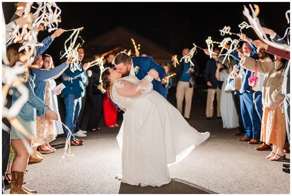 bride and groom dip back for a kiss during reception exit with ribbons