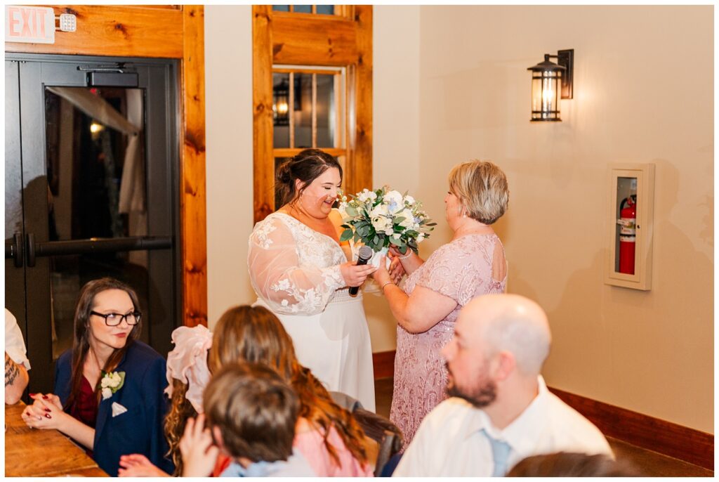 bride honoring her mom by giving her the bouquet at the wedding reception