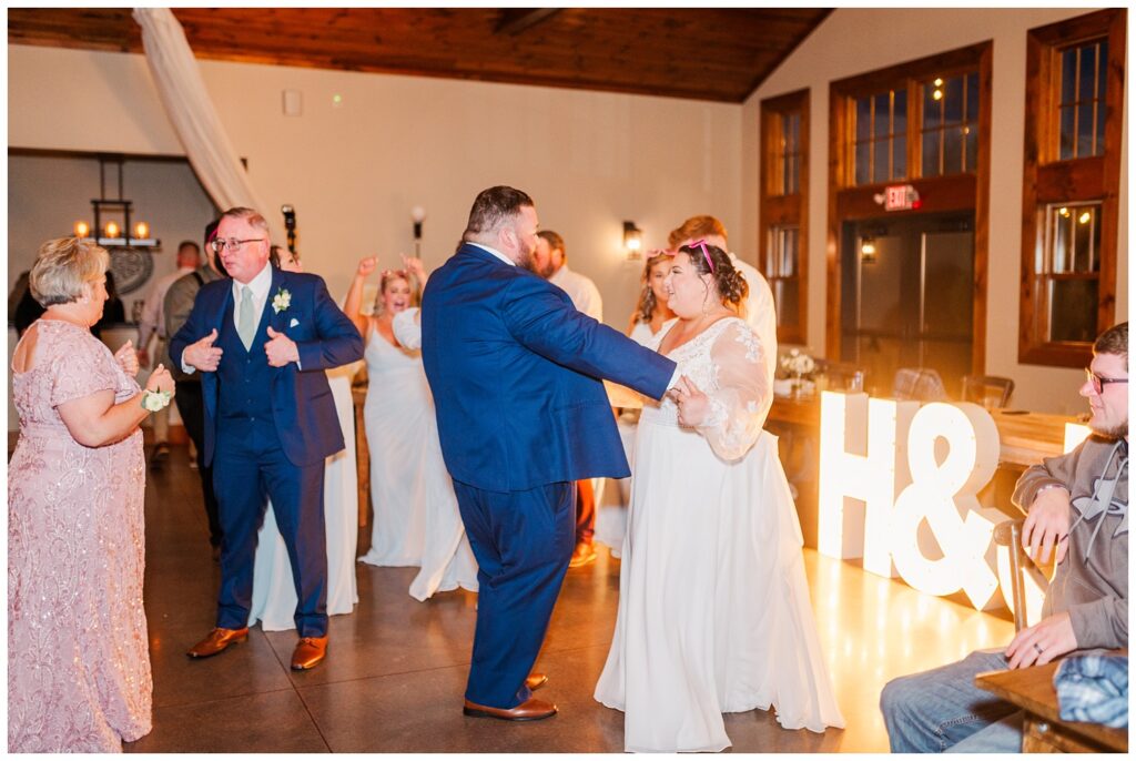 groom dancing with the bride in front of their light up letters 