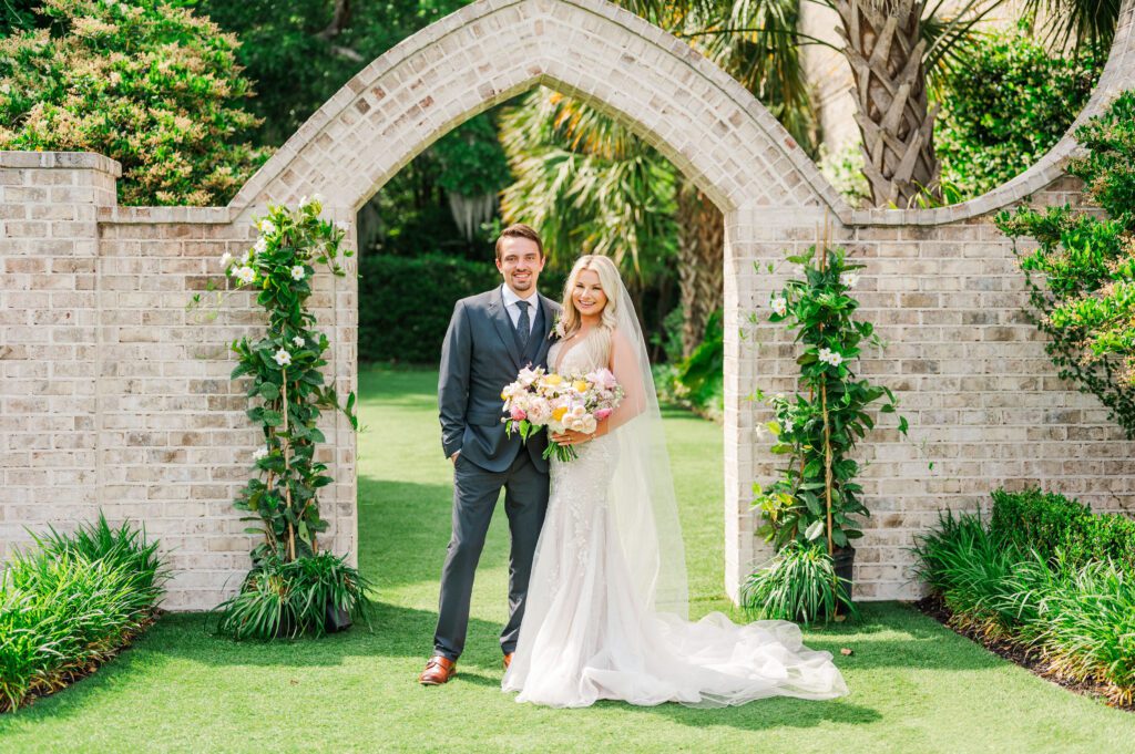 wedding couple standing in front of the brick arch at Wrightsville Manor