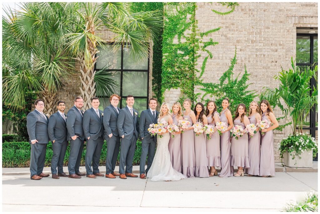 full wedding party posing outside in front of Wrightsville Manor in Wilmington