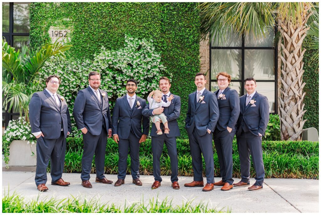 groomsmen holding the ring bearer and posing together outside the wedding venue in Wilmington