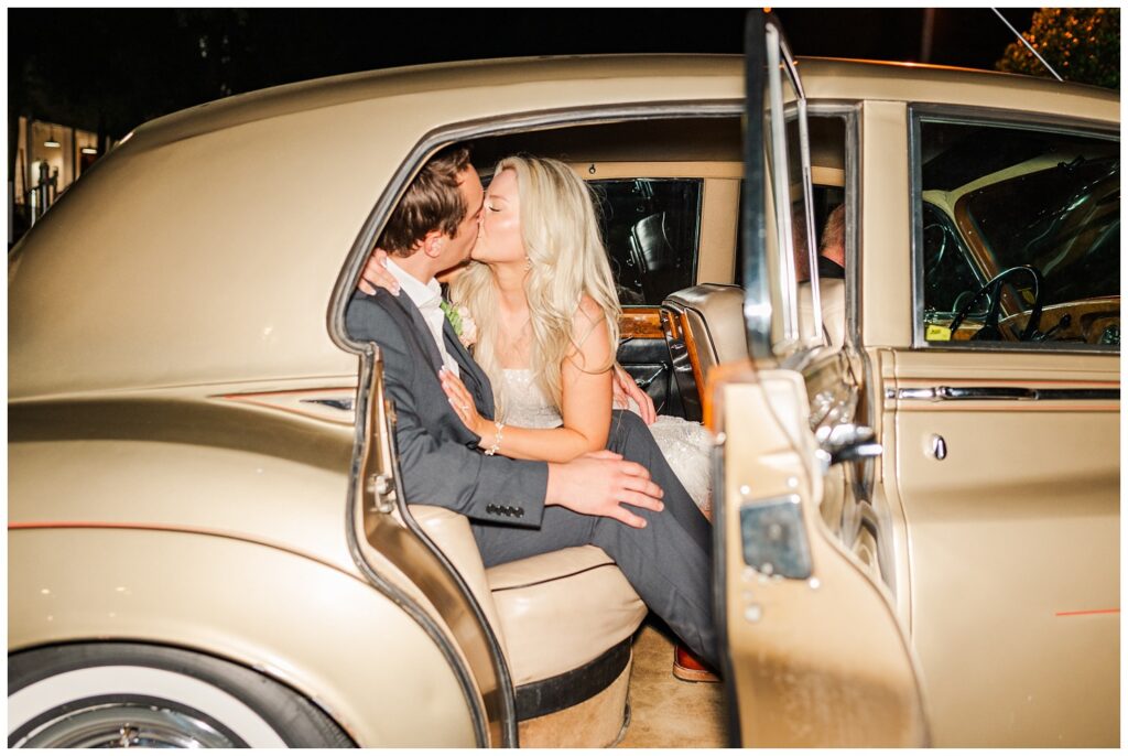 bride and groom kissing in the getaway car at Wilmington wedding reception