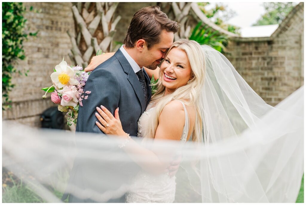 bride's veil wrapped around the front of the couple for spring wedding portraits 