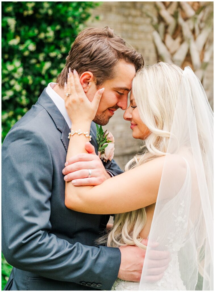 bride and groom posing with the bride's hand on the the groom's face 