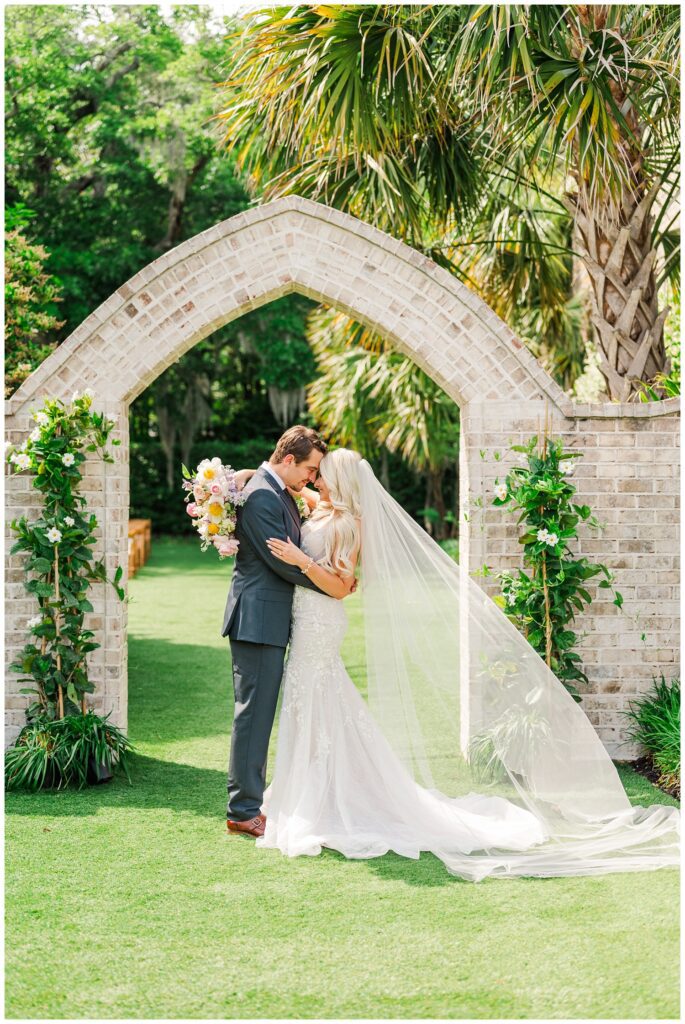 wedding couple touching foreheads in front of an arch at Wrightsville Manor